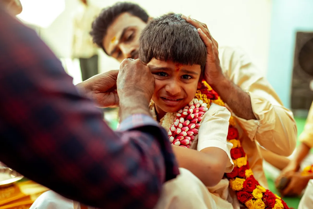 Family comforting a child during an ear piercing ceremony