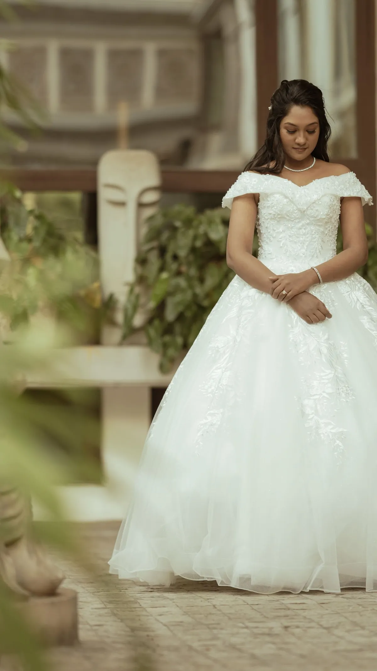 Bride in a white gown beside greenery